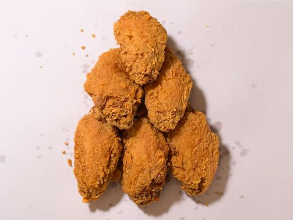 Several breaded fried chicken pieces stacked in a small pyramid on a white surface.