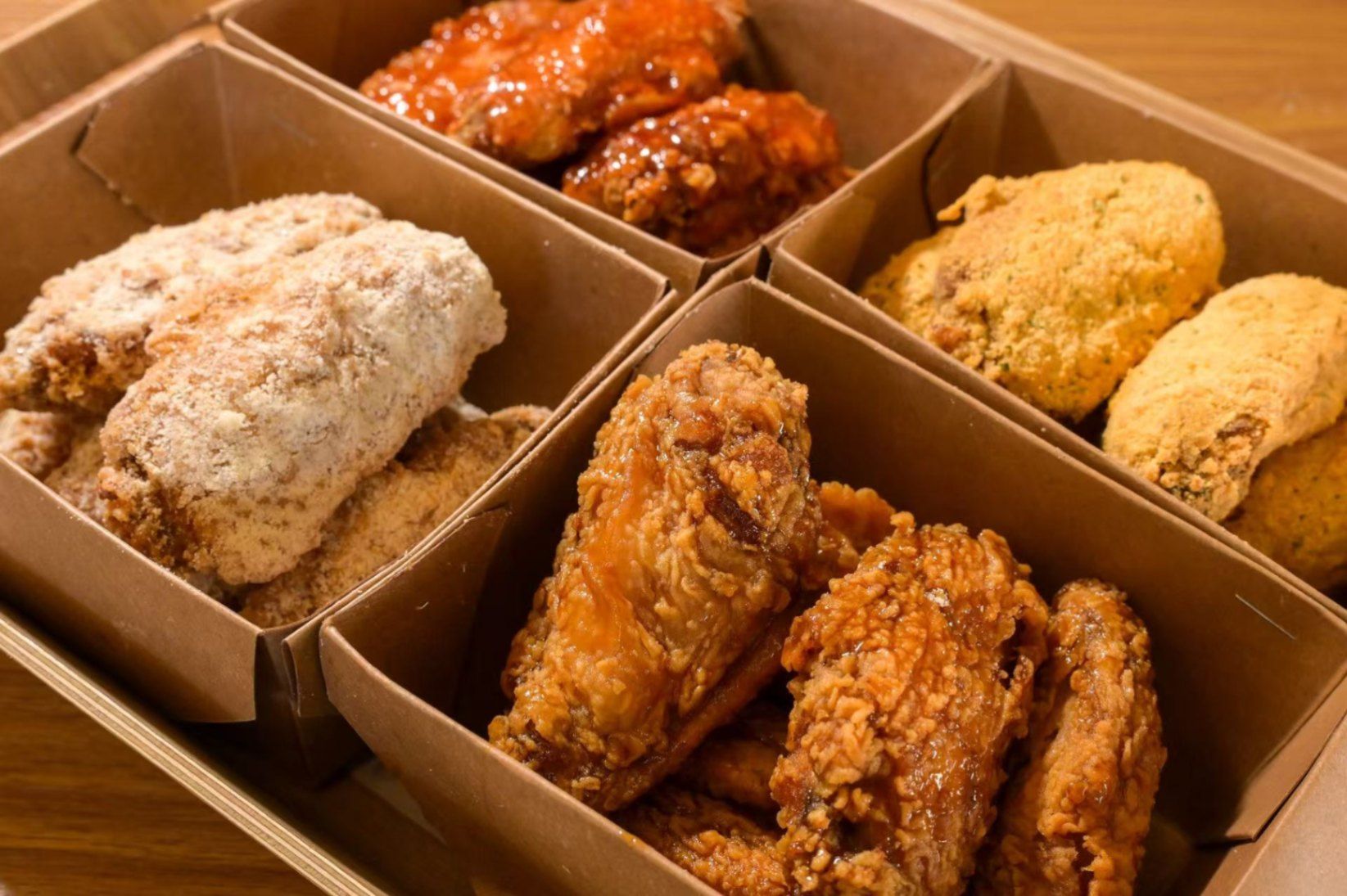 Boxed assortment of glazed, fried chicken wings in cardboard takeout containers
