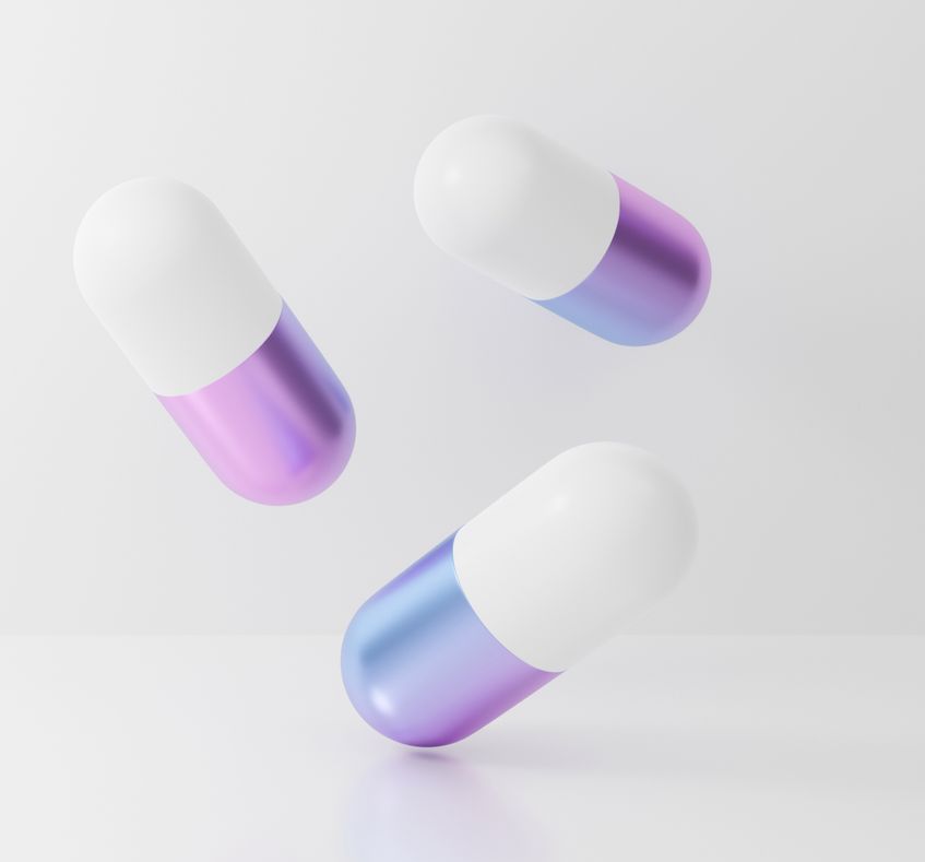 Three purple and white pills are floating in the air on a white surface.