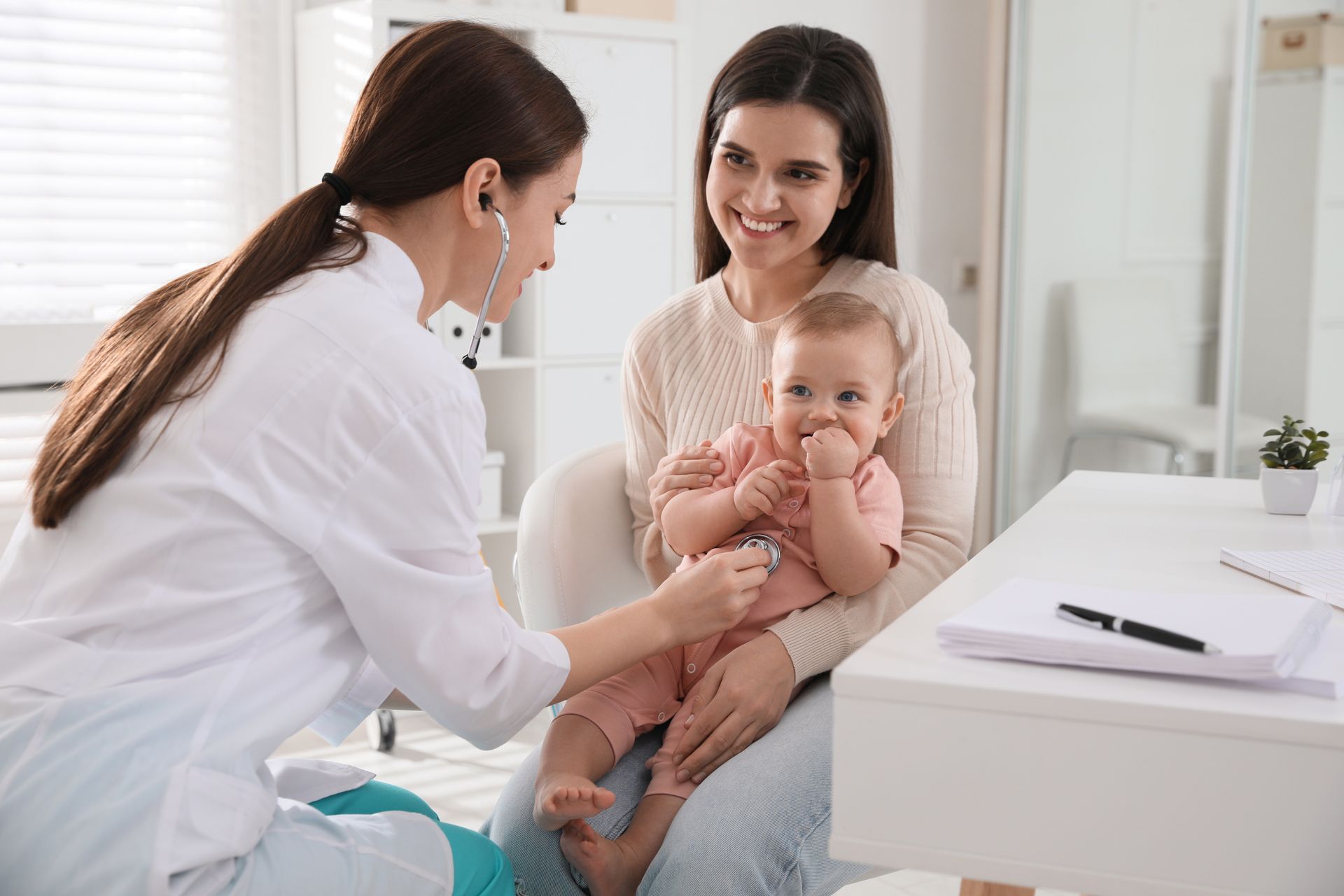 A doctor is examining a baby with a stethoscope in a hospital.