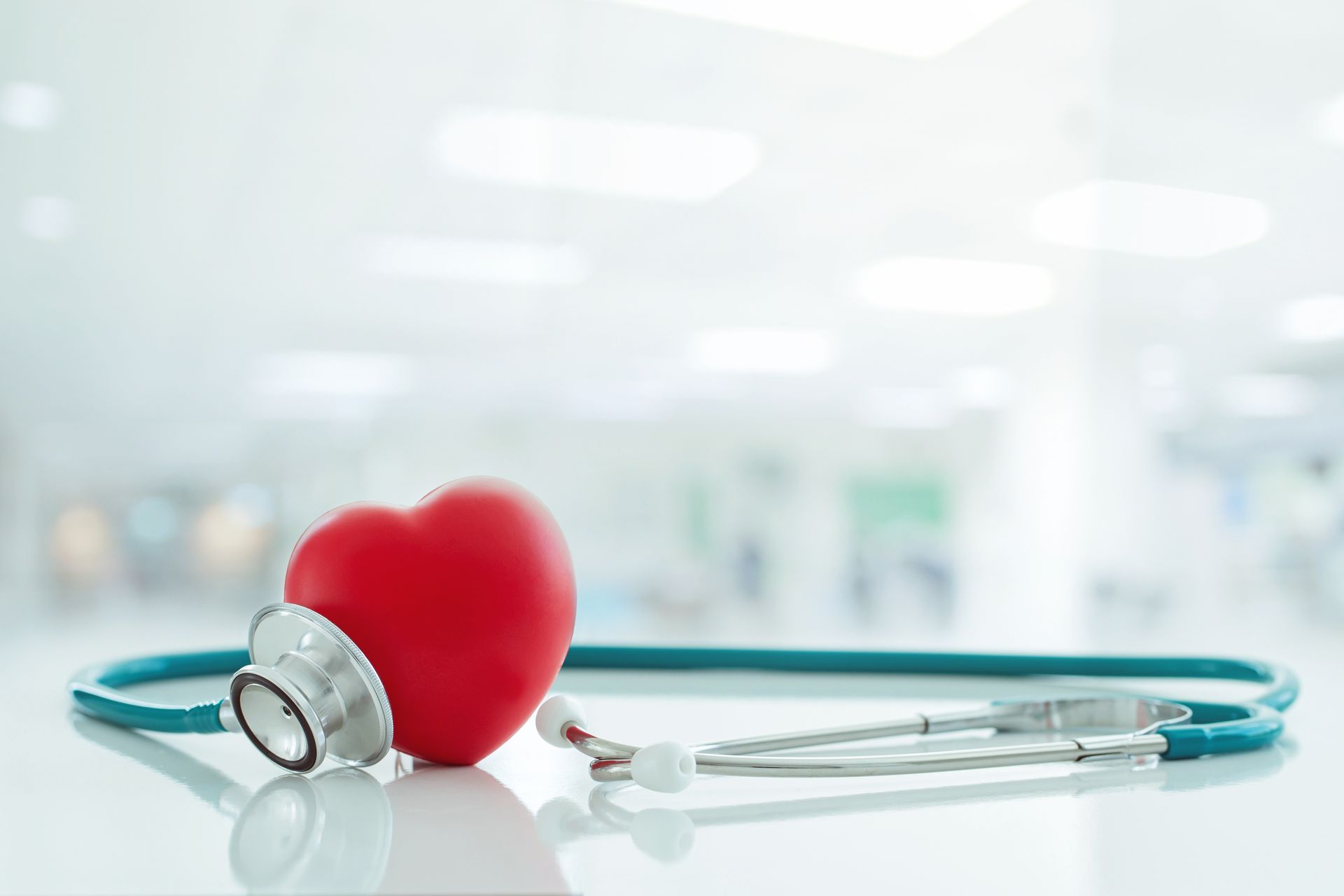 A red heart is sitting next to a stethoscope on a table.