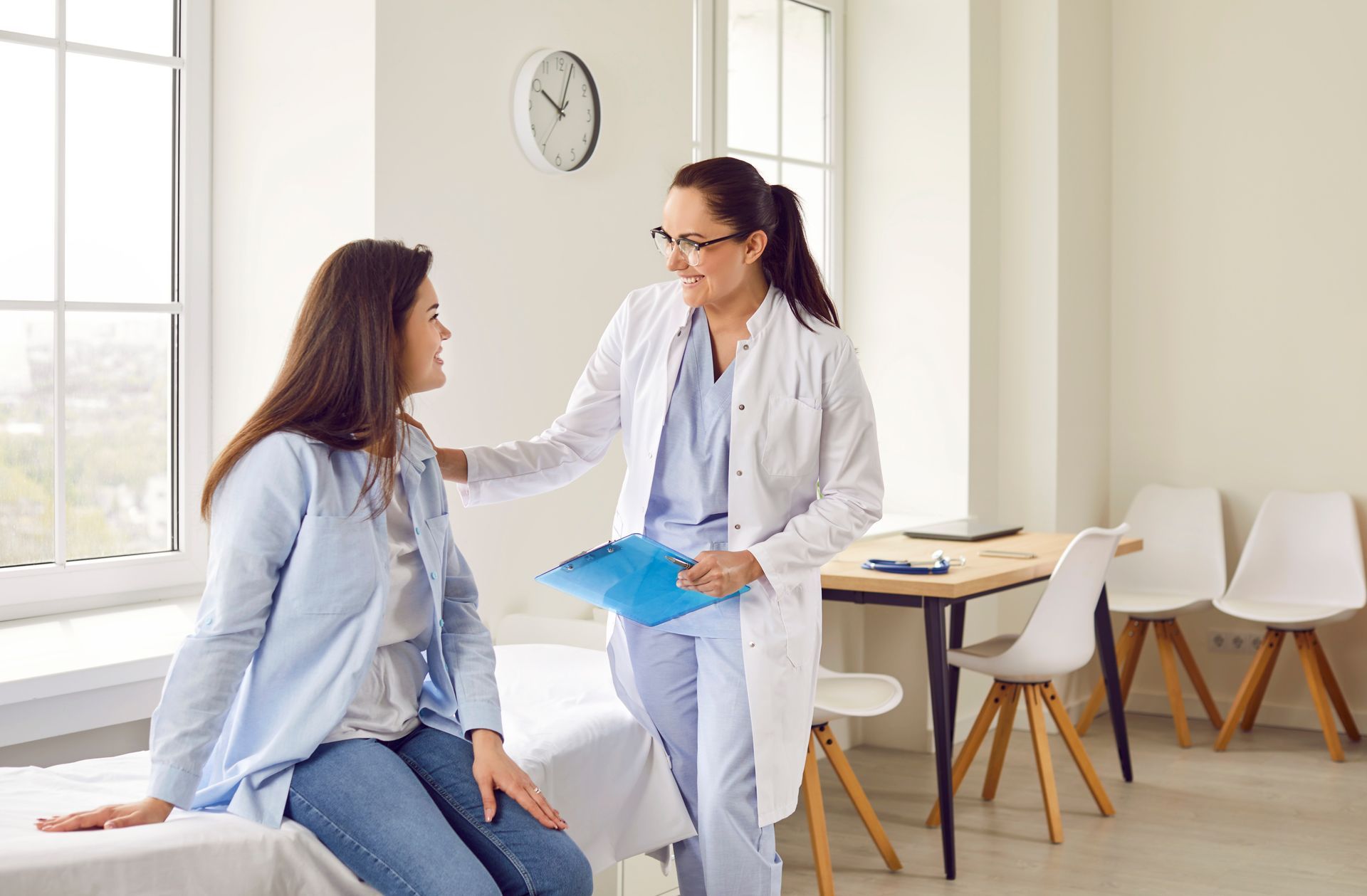 A doctor is talking to a patient who is sitting on a bed.