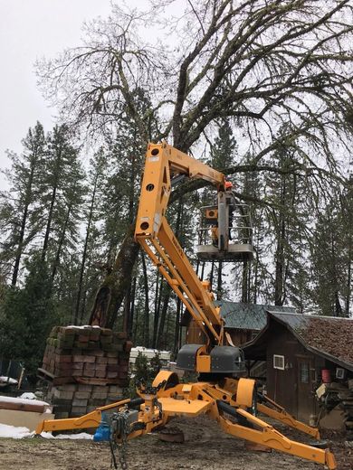 Yellow crane lifting a house section in a snowy wooded yard
