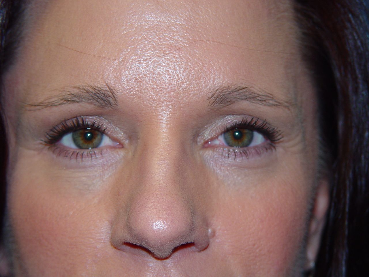 A close up of a woman 's face with green eyes and a nose.