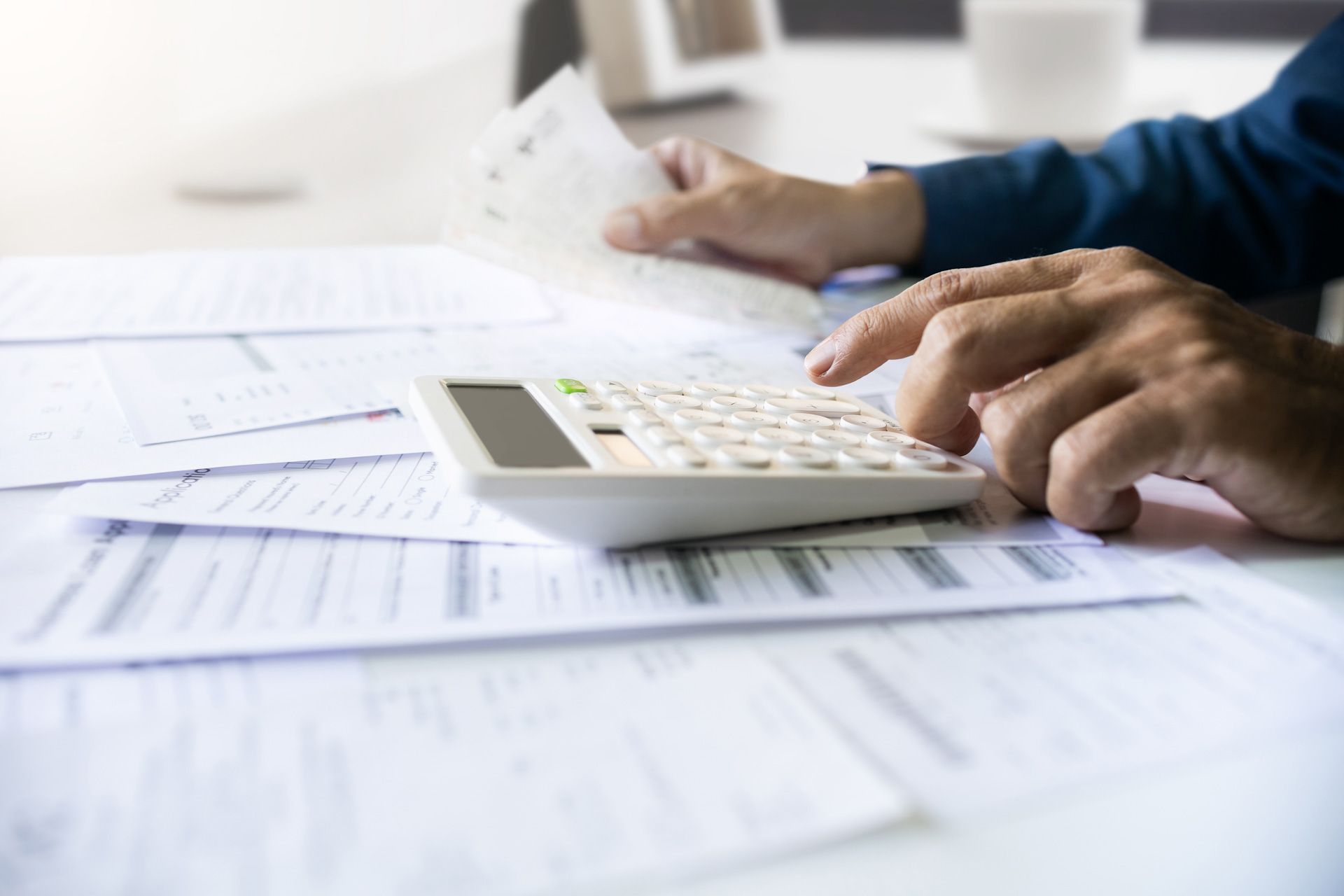 A person is using a calculator while holding a piece of paper.