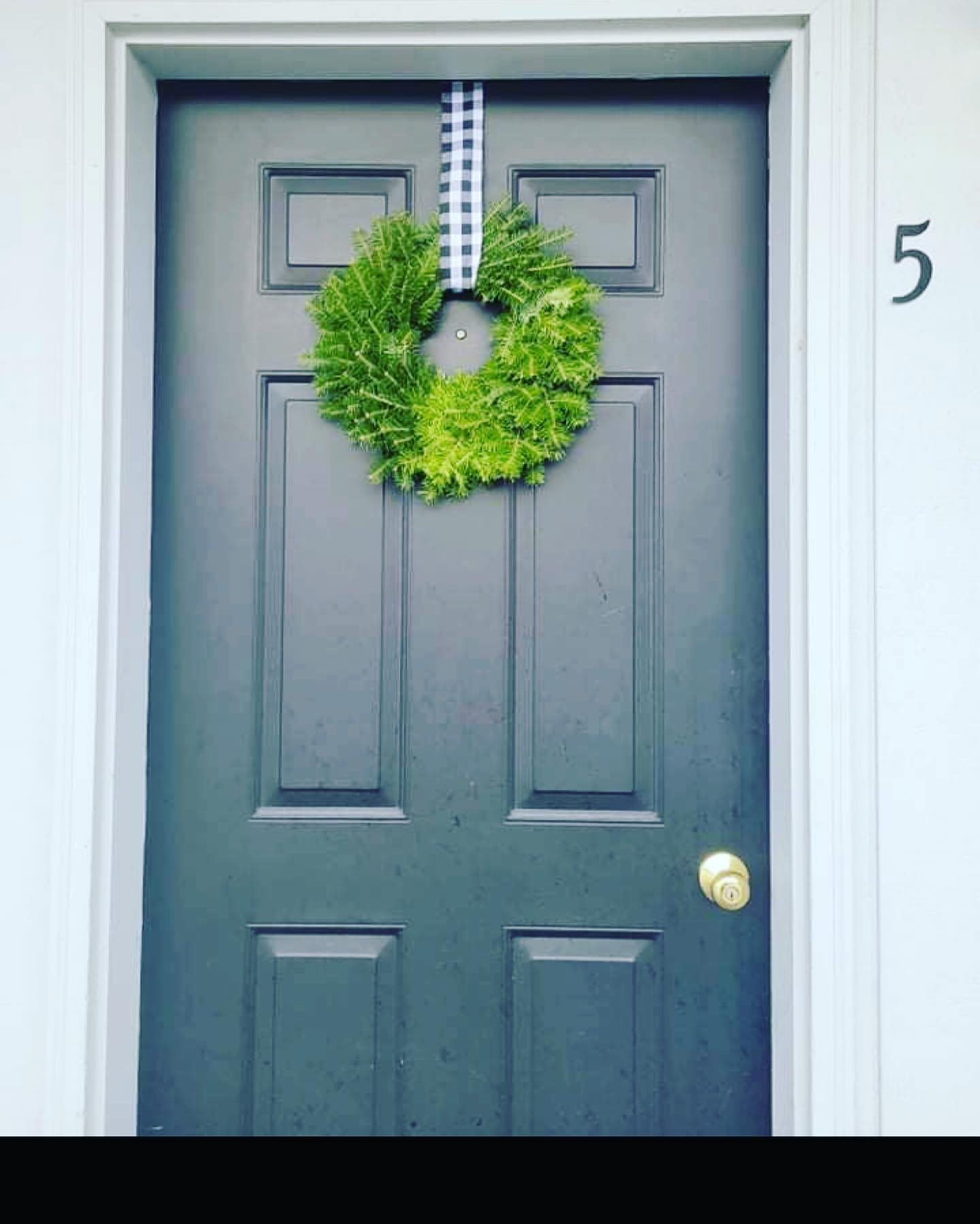 Gray front door with green wreath and house number 5