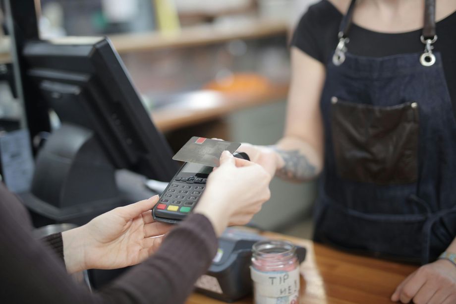 A customer uses a chip card to pay on a portable card reader held by a shop employee.