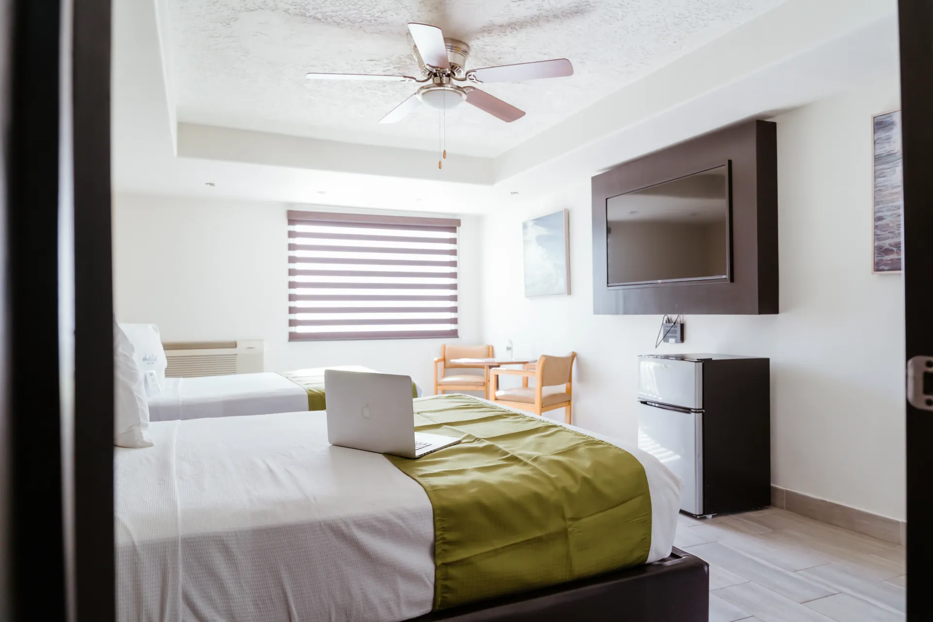Una habitación hotel Siesta Real Mexicana con dos camas, un ventilador de techo y un televisor de pantalla plana.