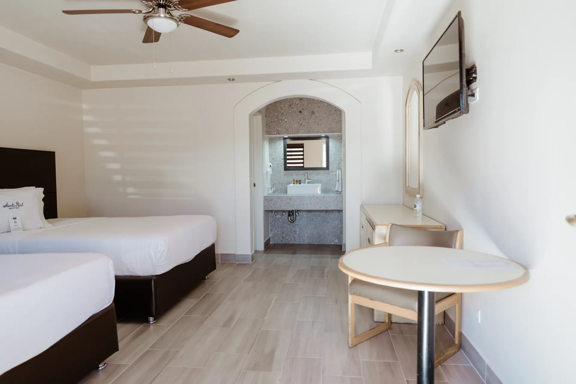 Una habitación del hotel Siesta Real Mexicana con dos camas, una mesa y un televisor.