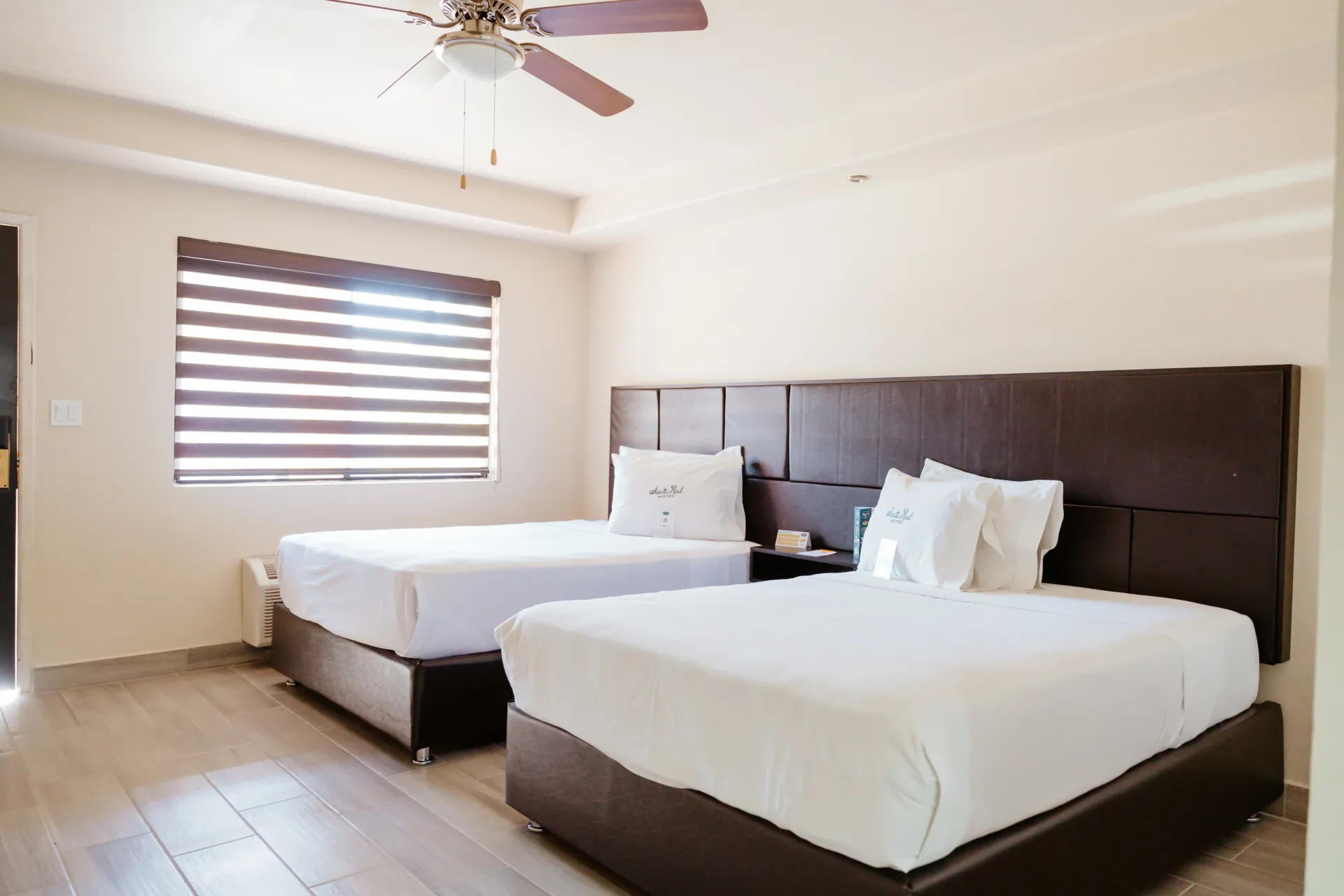 Una habitación de hotel con dos camas y un ventilador de techo.