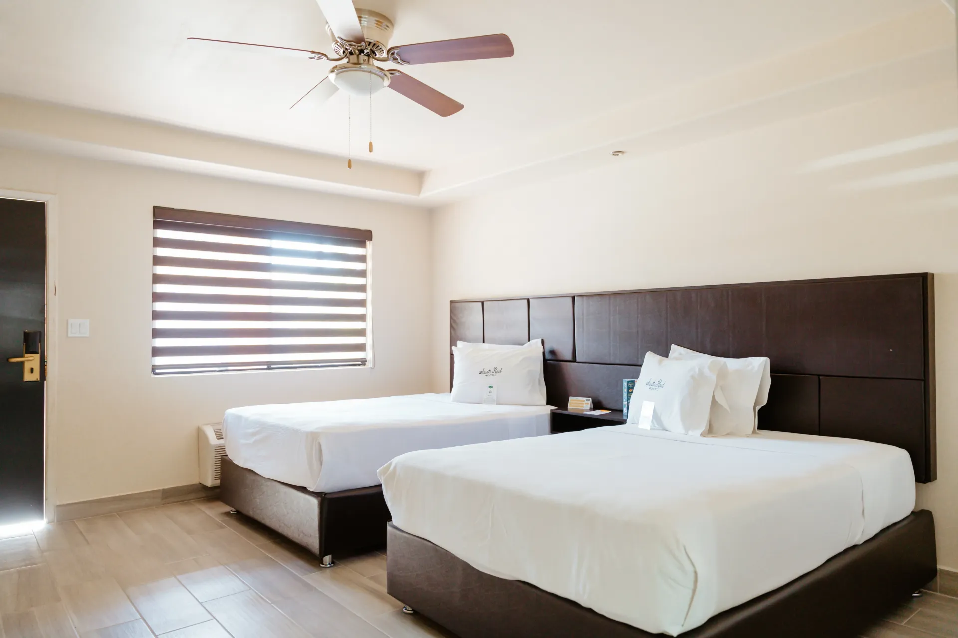 Una habitación de hotel con dos camas y un ventilador de techo.