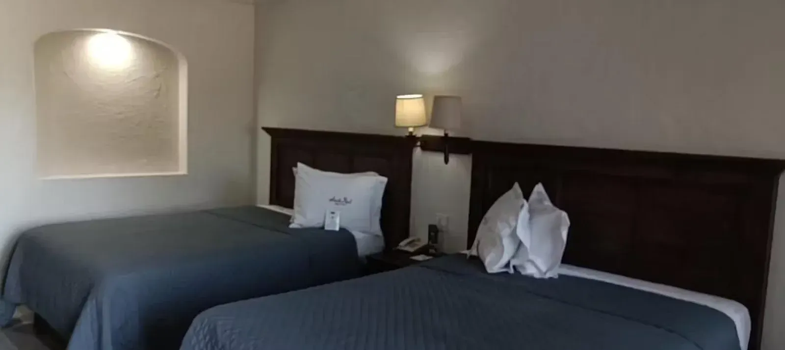 Una habitación del hotel Siesta Real Mexicana con dos camas y una lámpara.