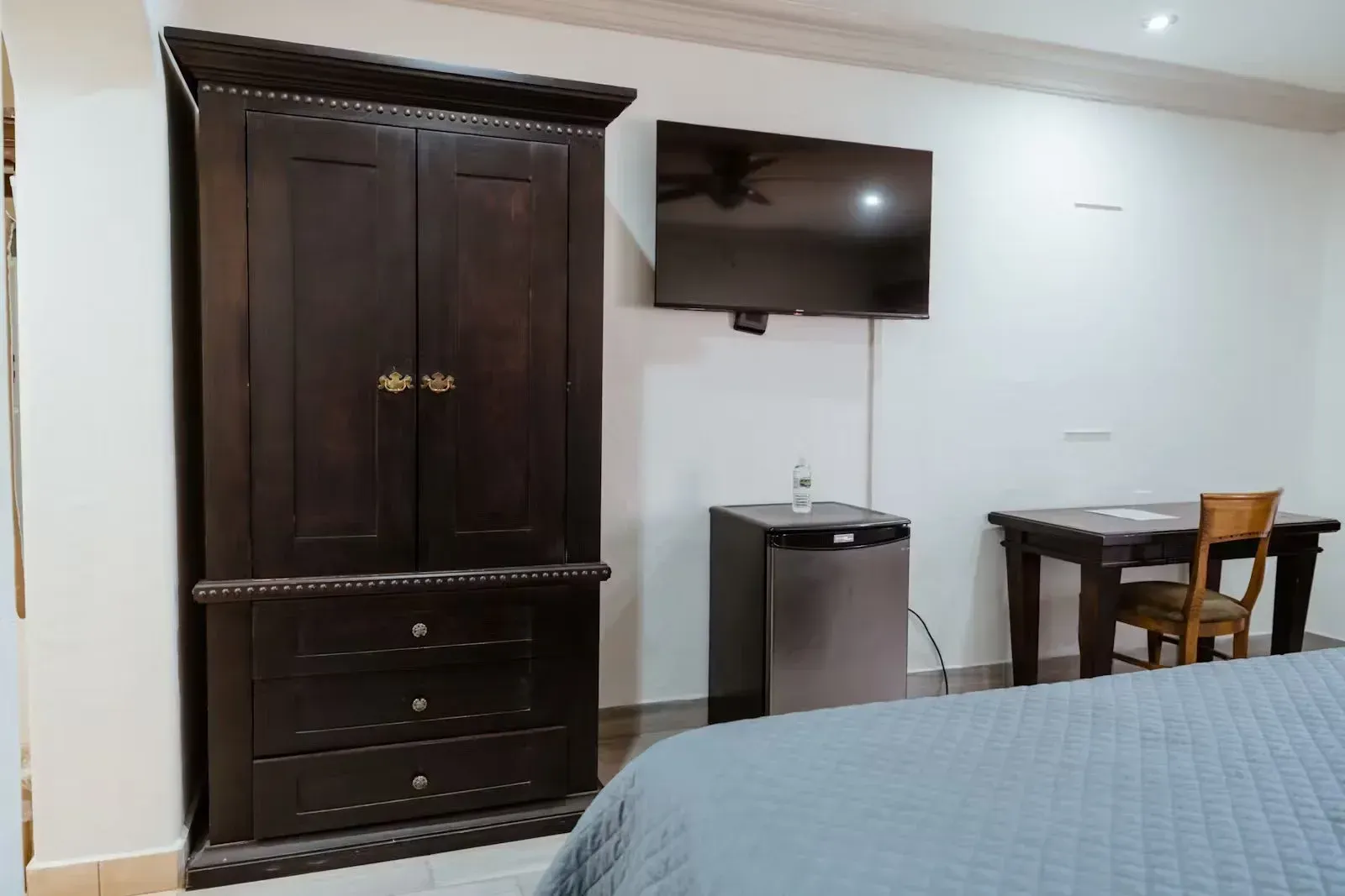 Una habitación de hotel con cama, tocador, escritorio y televisión.