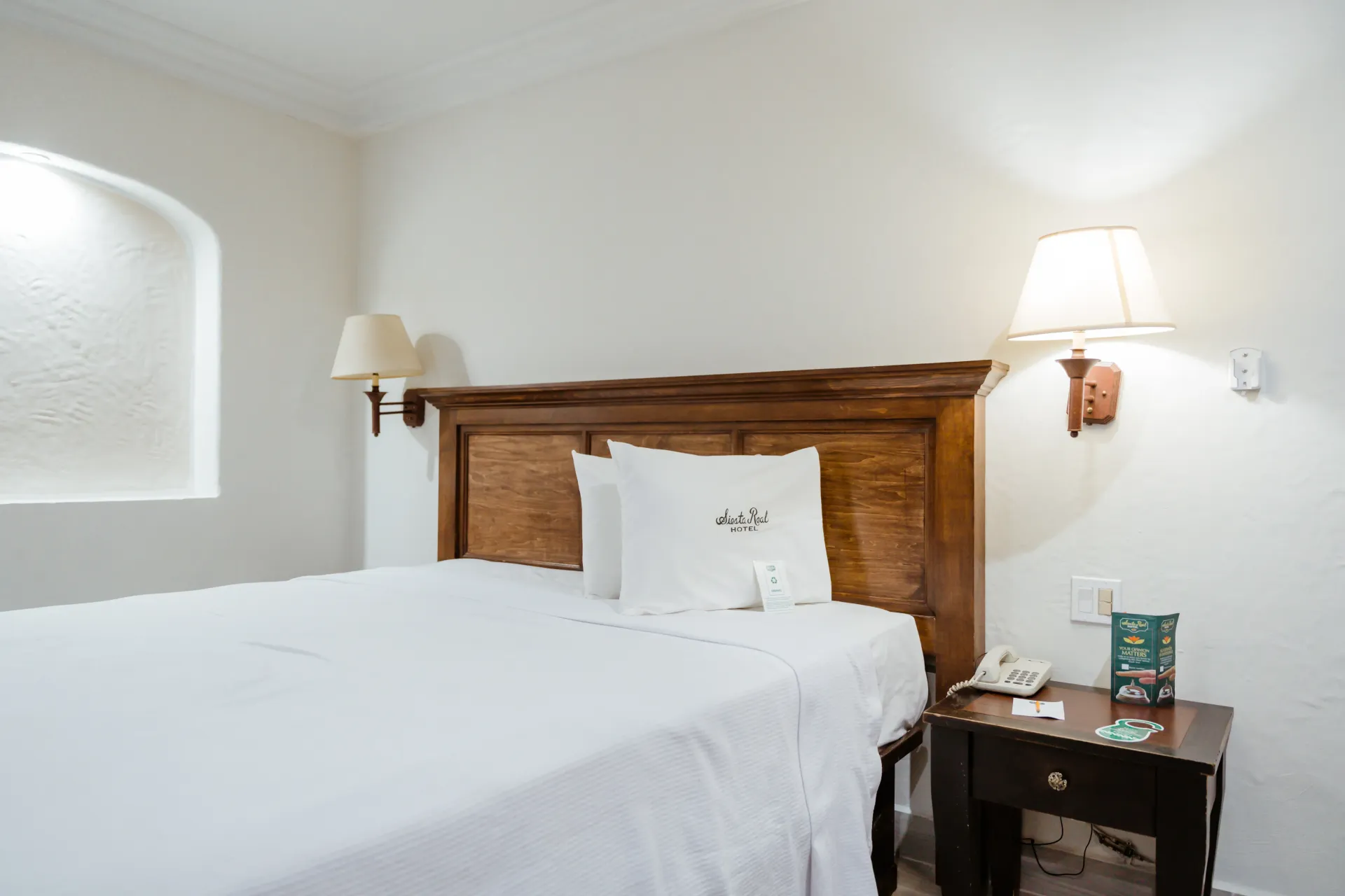 Una habitación del hotel Siesta Real Mexicana con una cama tamaño king y una mesita de noche.