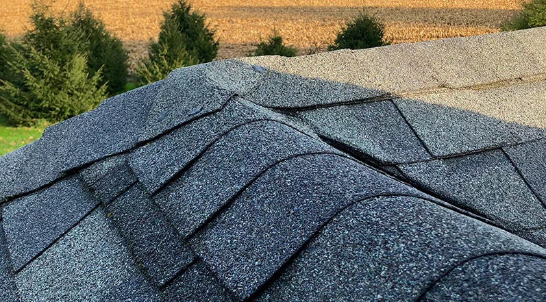 Water spilling off a brown tiled roof above a light gray wall.