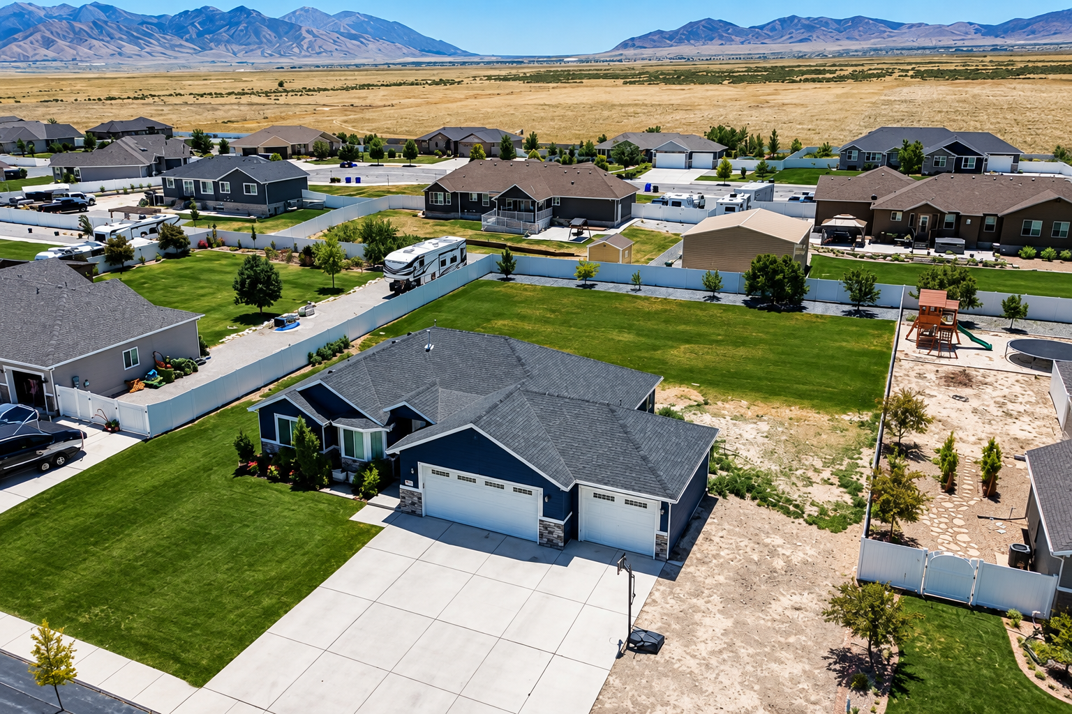 A modern gray-roofed house with a two-car garage in a desert neighborhood under a clear sky.