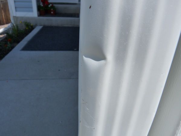 Close-up of a gray floor with a lifted seam or torn edge exposing the layer beneath
