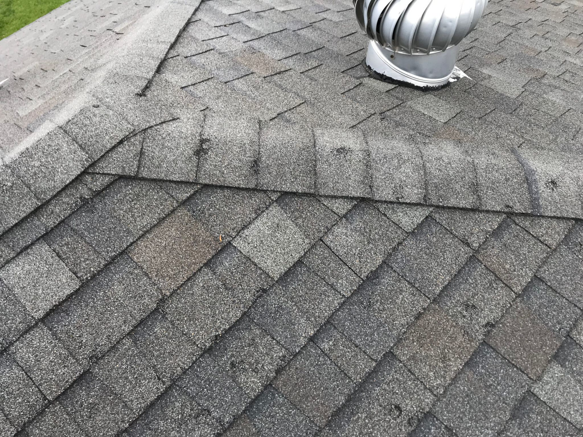 Damaged terracotta roof tiles with cracks and missing pieces on a house roof