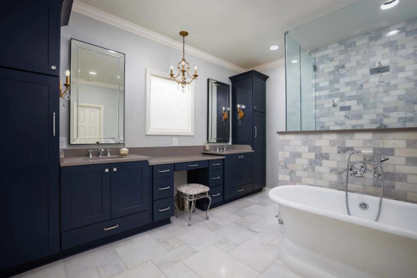 Navy blue bathroom with double vanity, tall cabinet, soaking tub, glass shower.