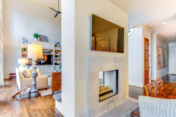 Living room with fireplace and mounted TV on a white wall, adjacent to a dining area.