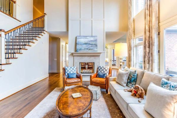 Living room with high ceilings, fireplace, staircase, furniture, and large windows.
