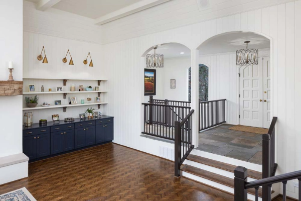 Interior with white walls, arched doorways, a dark blue cabinet, and hardwood floors.