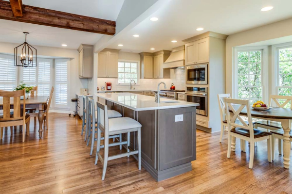 Spacious kitchen with wood floors, island with seating, cabinets, and a dining area.
