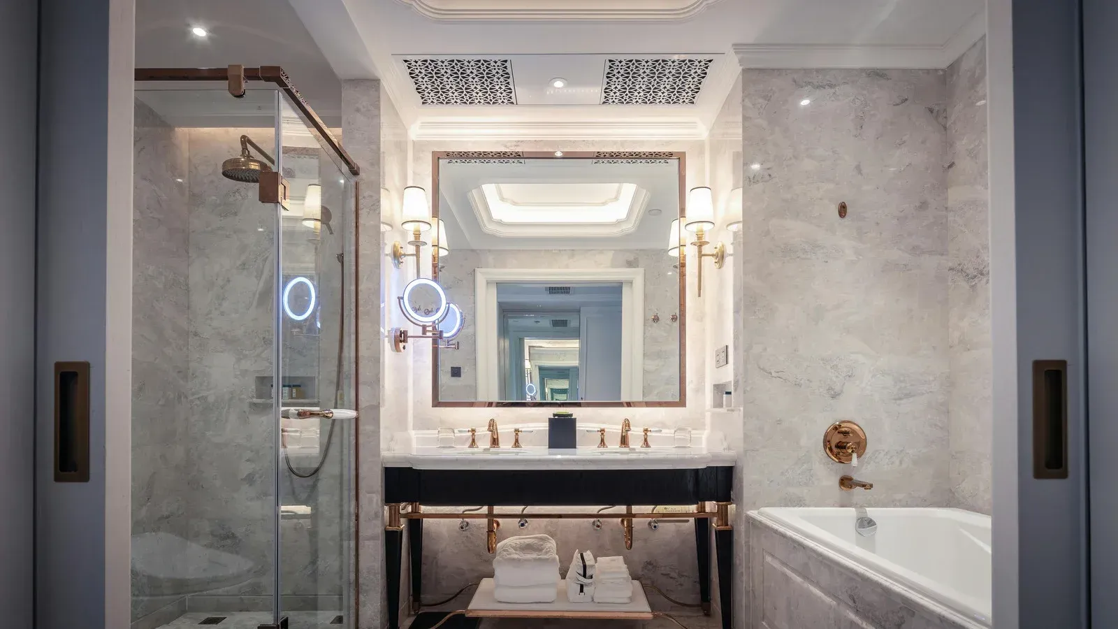 Luxurious marble bathroom with glass shower, double vanity, and soaking tub.