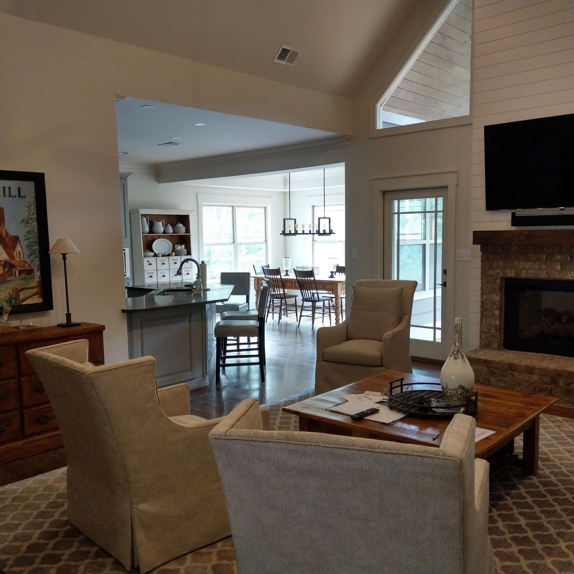 Living room with fireplace, chairs, and view into the kitchen and dining area.