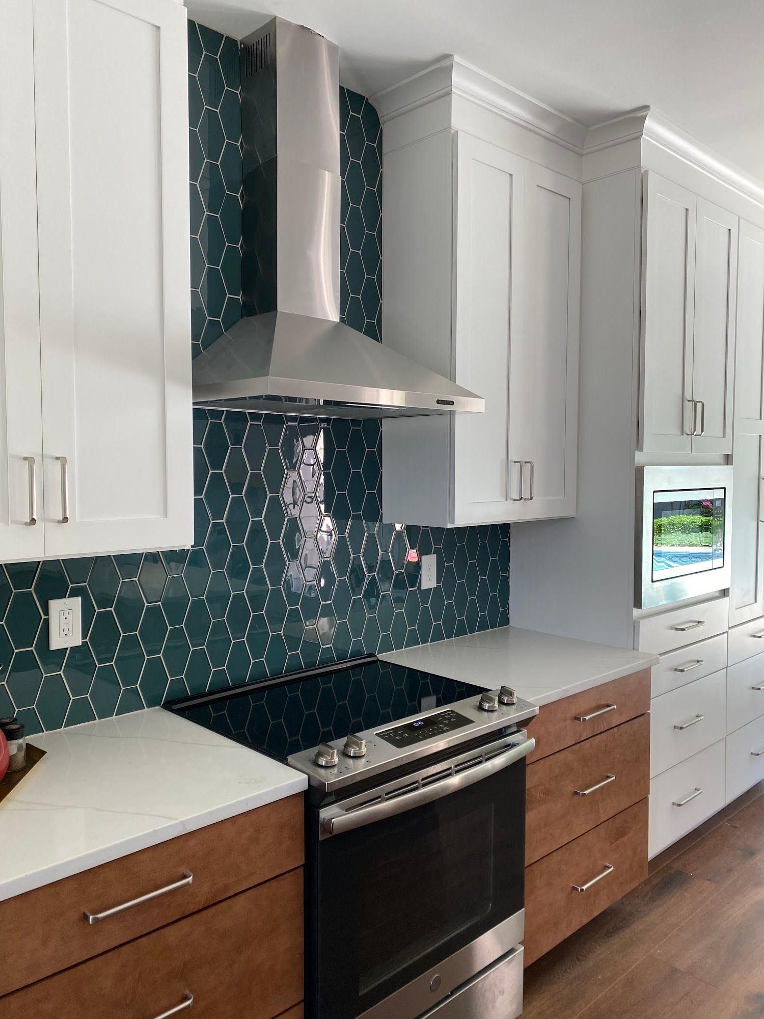 Kitchen with white cabinets, wood lower cabinets, green backsplash, and stainless steel appliances.