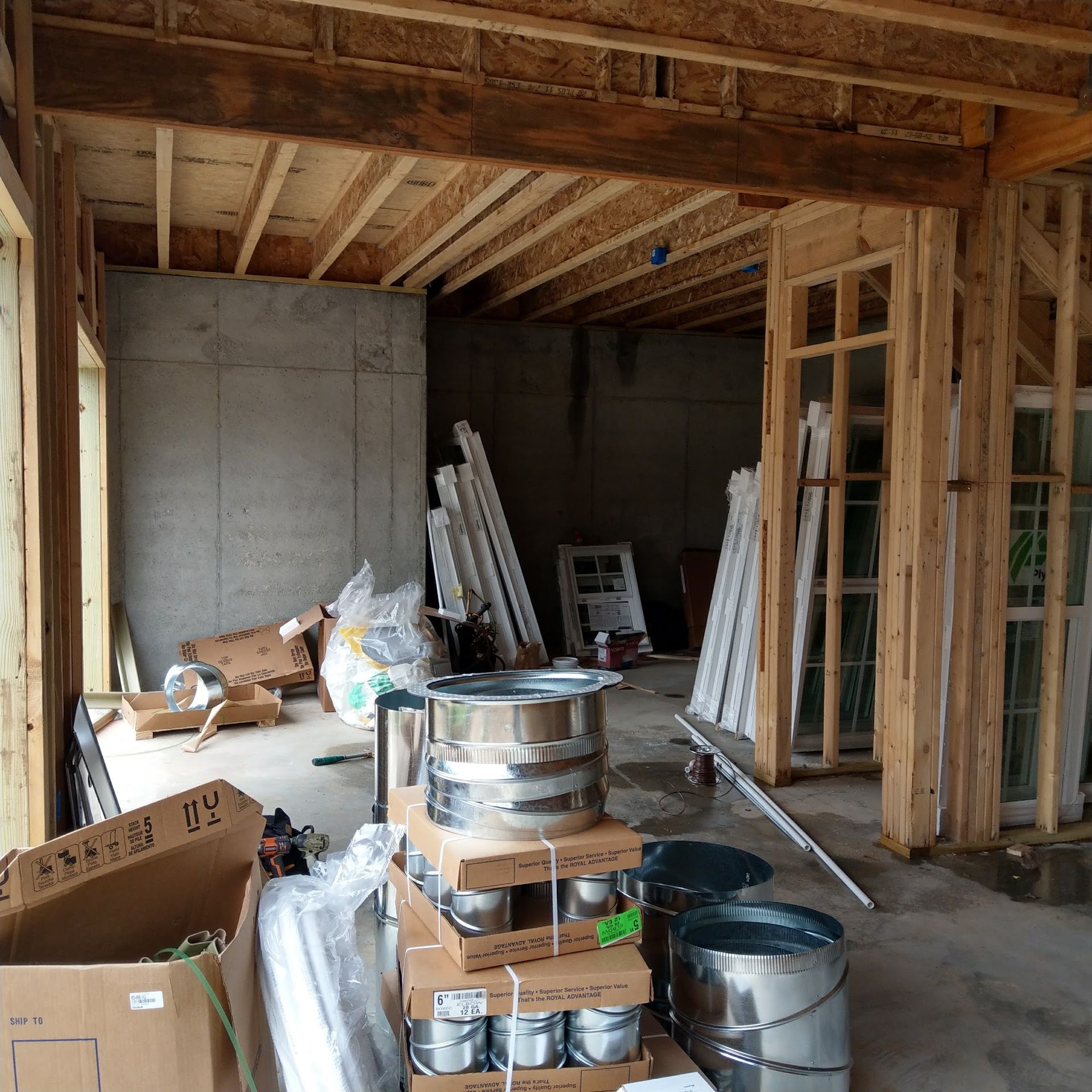 Interior of a building under construction, showing wooden framing, concrete walls, and materials scattered around.