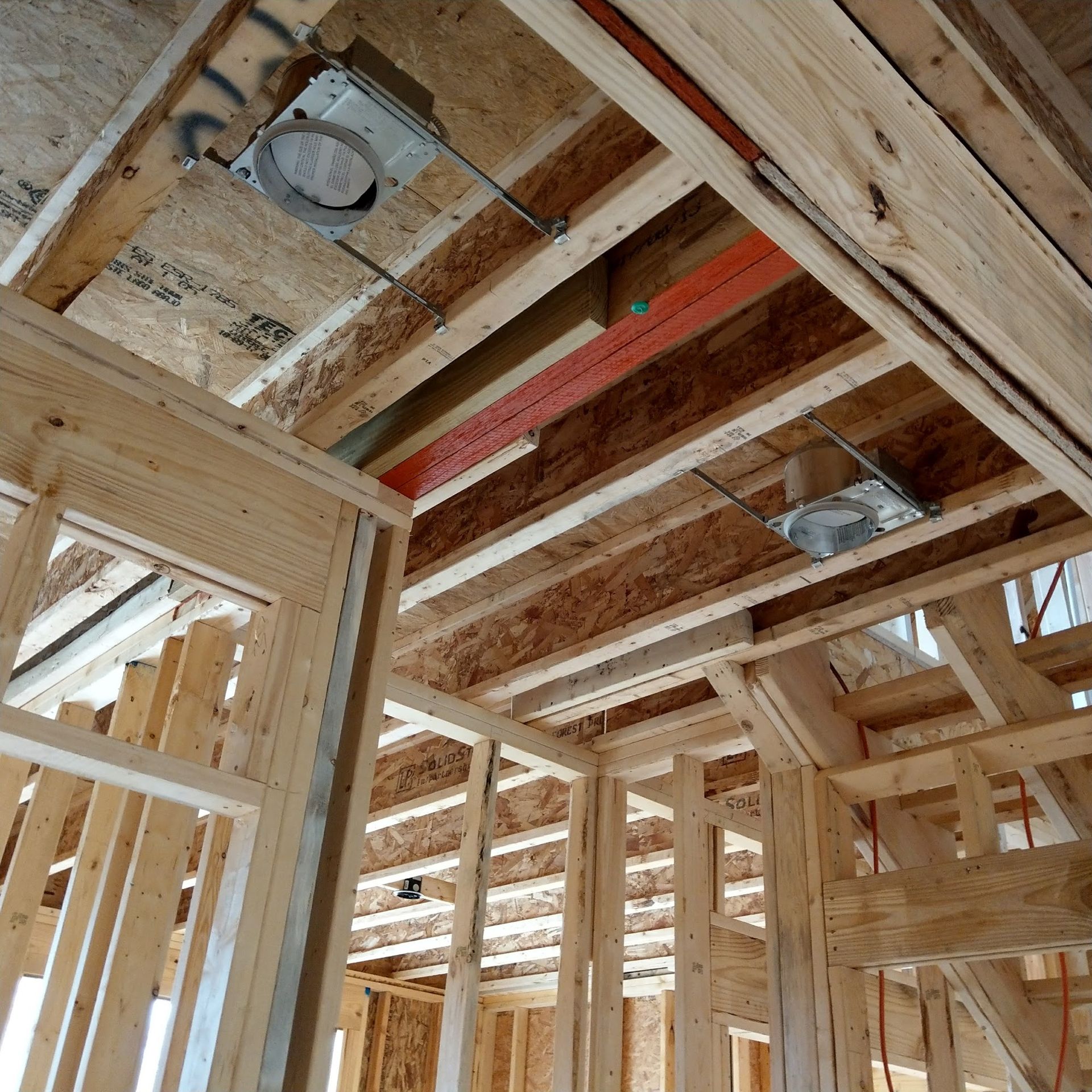Unfinished interior of a building under construction, showing wooden framework and recessed ceiling lights.