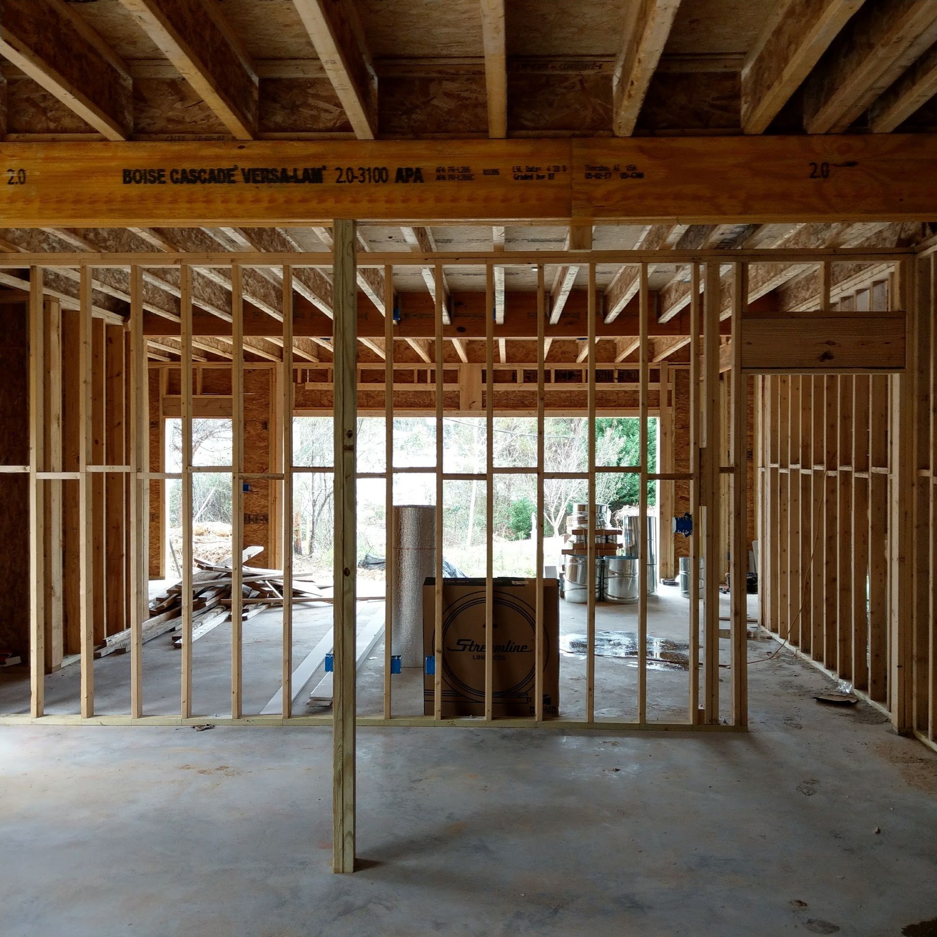 Interior of a building under construction, showing wooden framing and concrete floor.