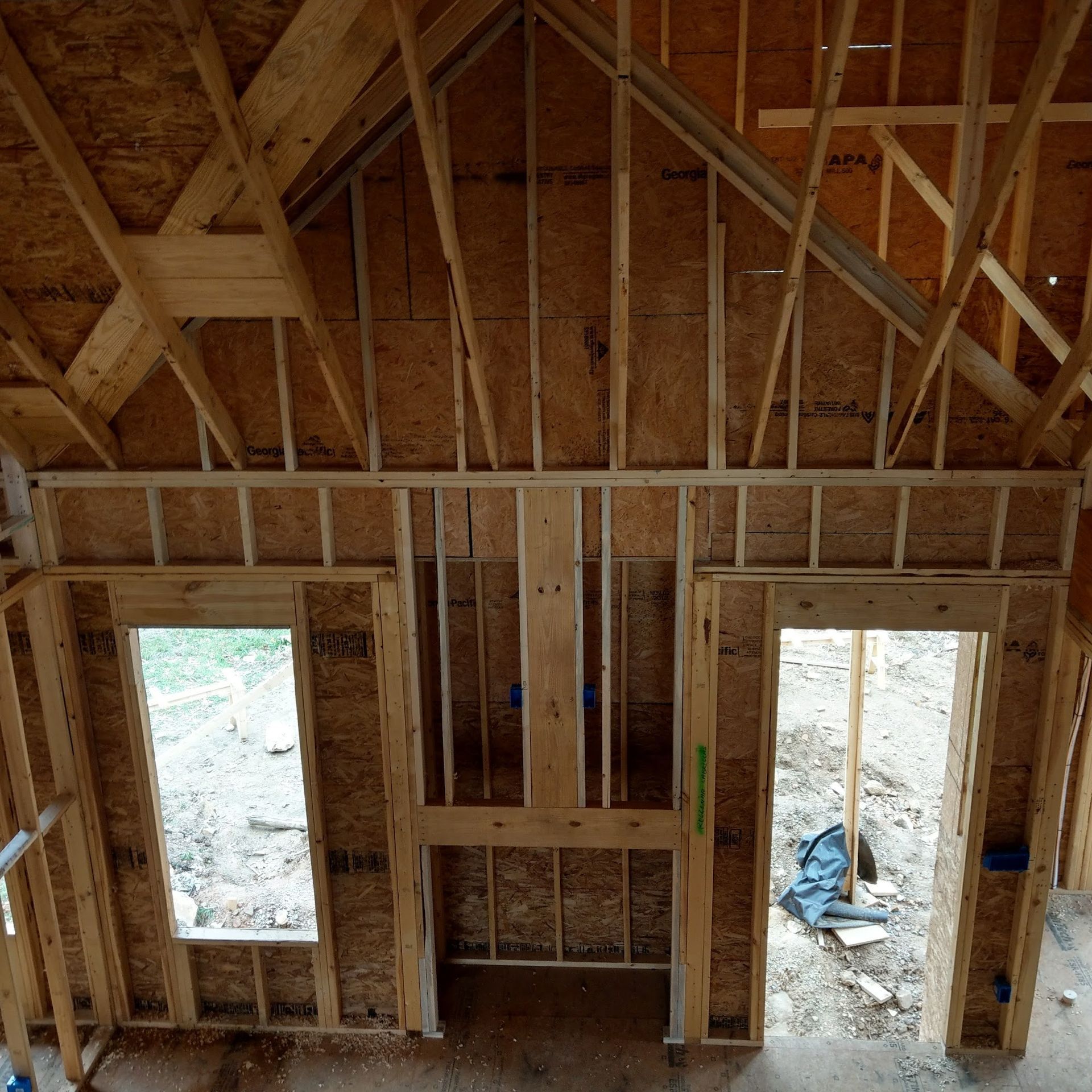 Interior framing of a house with window and fireplace openings. Wooden beams are visible.