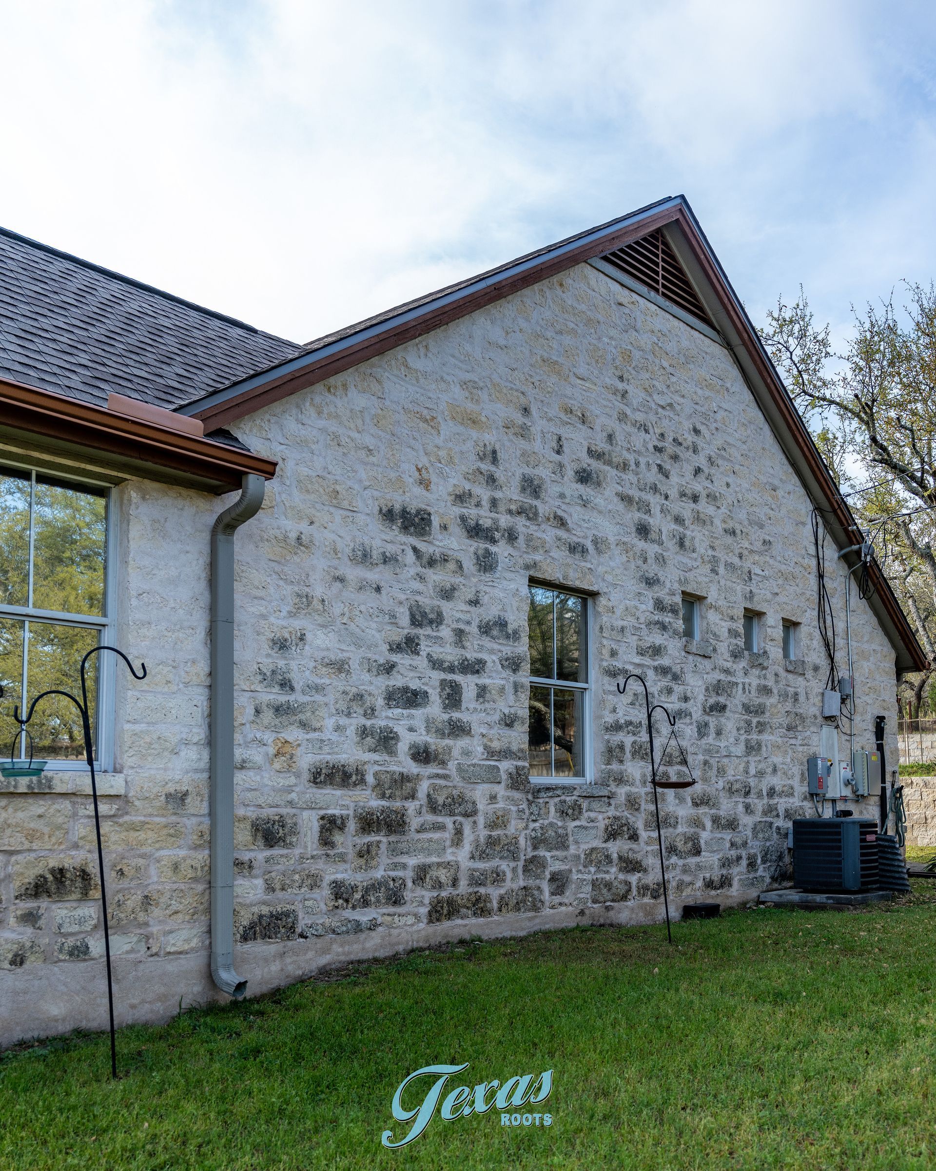 Algae buildup on stone house exterior in Dripping Springs Texas before cleaning