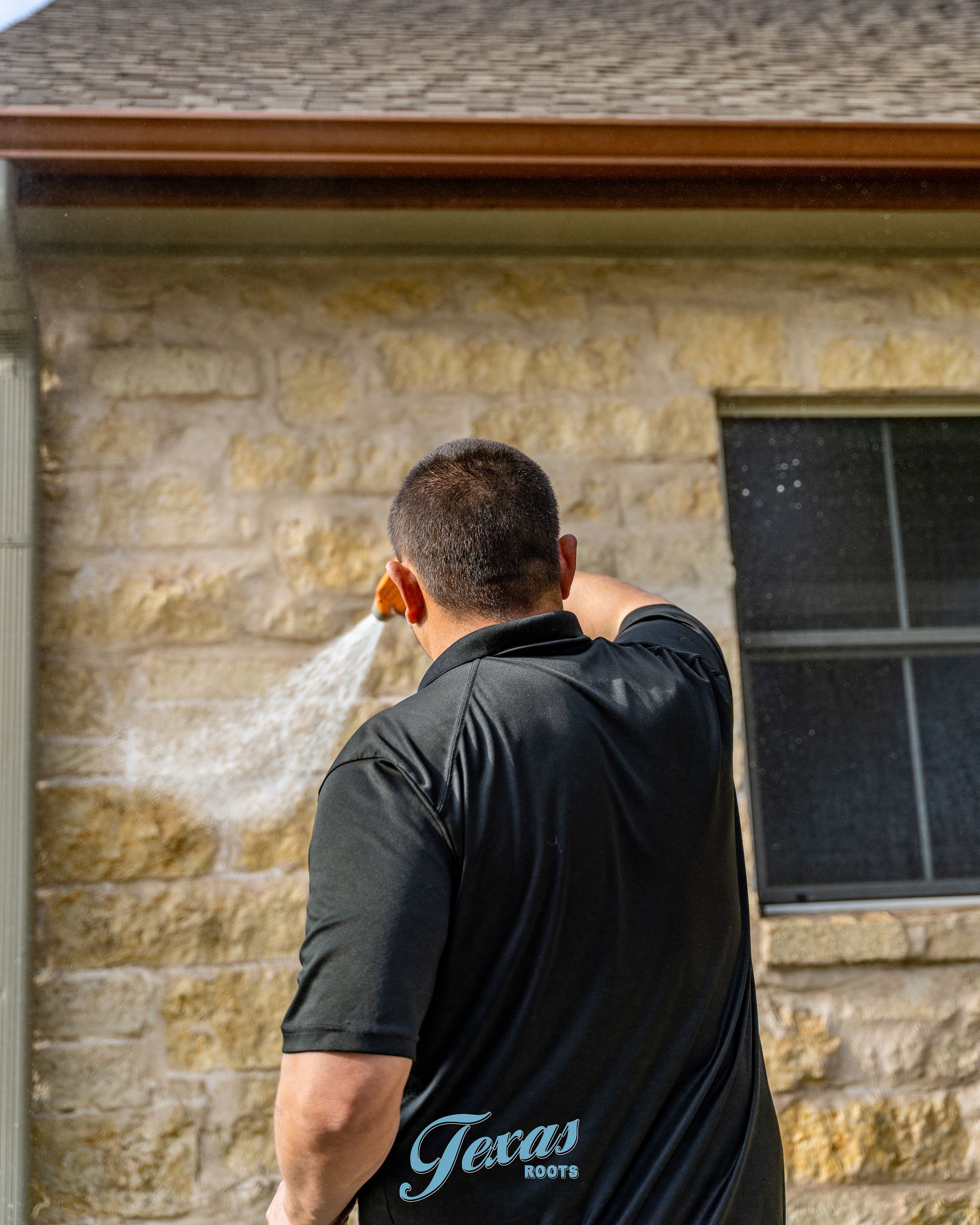 Soft washing application on stone siding in Dripping Springs home