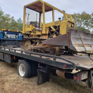 A yellow bulldozer is sitting on top of a tow truck.