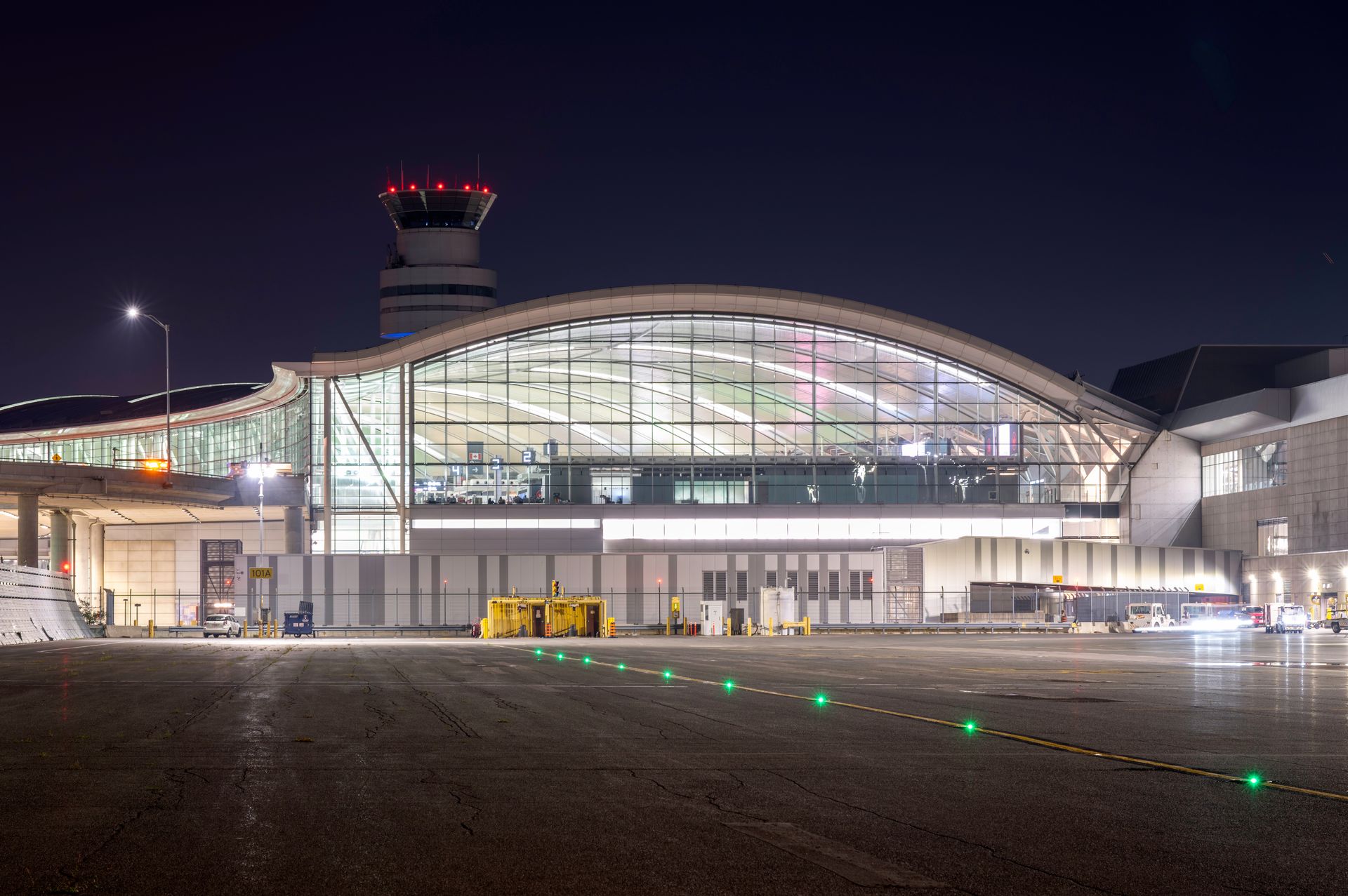 A spacious airport terminal illuminated at night, featuring bright overhead lights