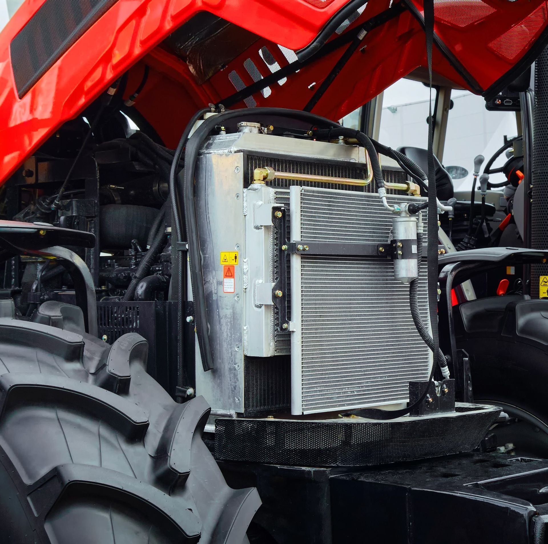 Close-up of a red tractor engine bay with exposed radiator and large rear tire.