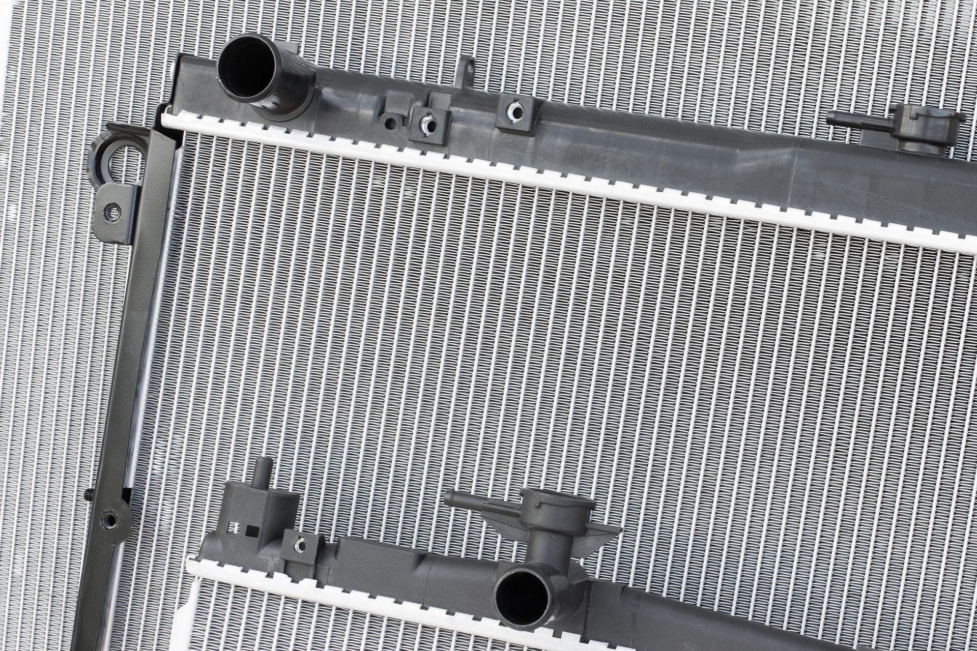 Close-up of a silver radiator with black plastic frame on a textured gray surface Close-up of a silver radiator with black plastic frame on a textured gray surface