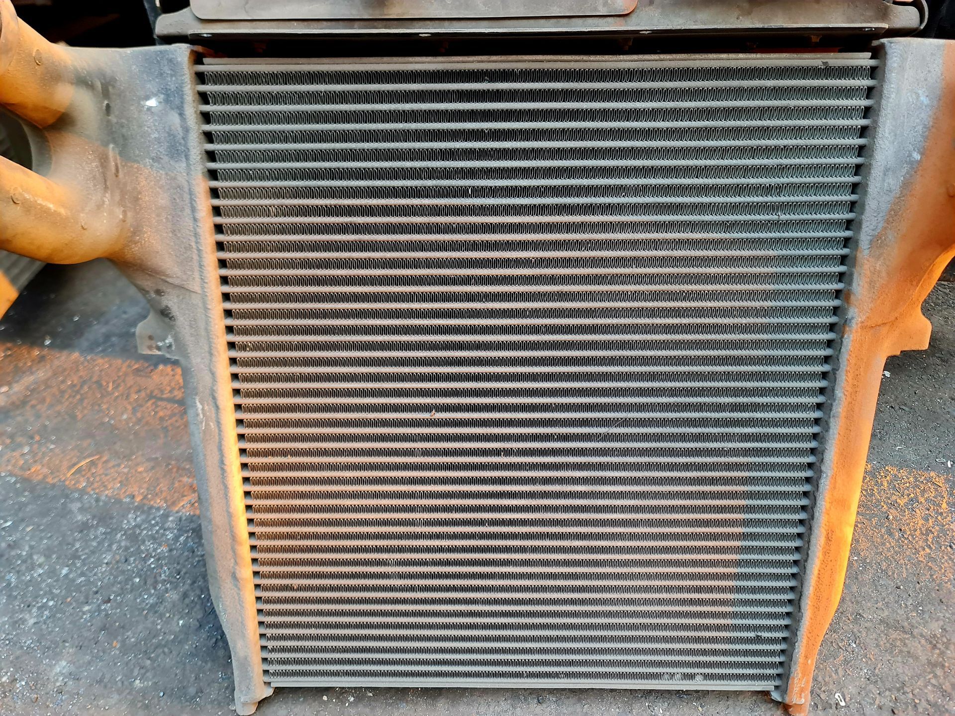 Close-up of a dusty truck radiator and grille with orange side panels