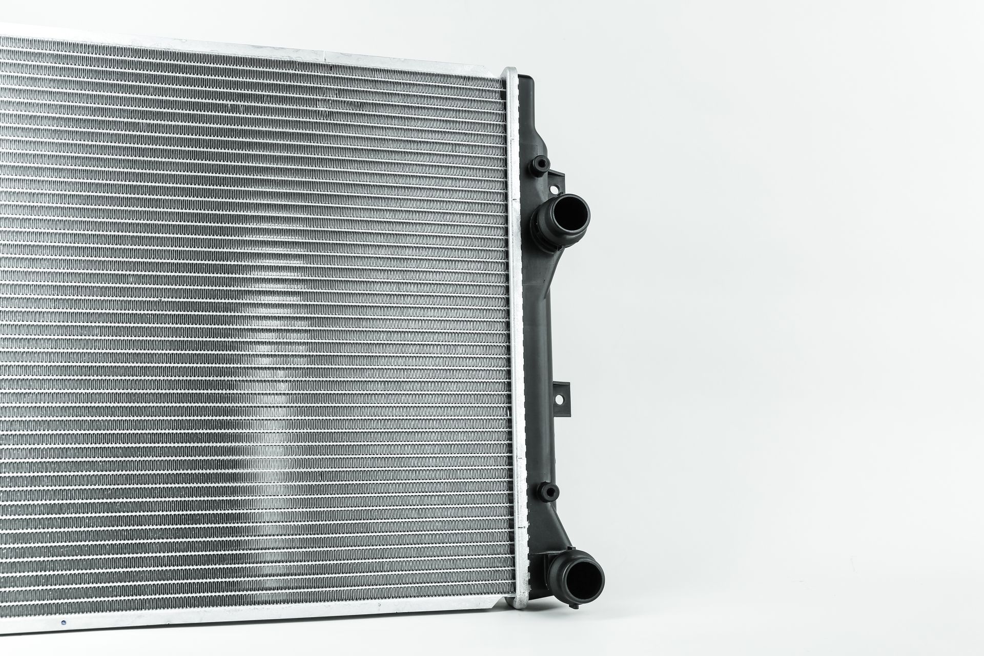Close-up of a silver radiator with black hose connections on a white background Close-up of a silver radiator with black hose connections on a white background