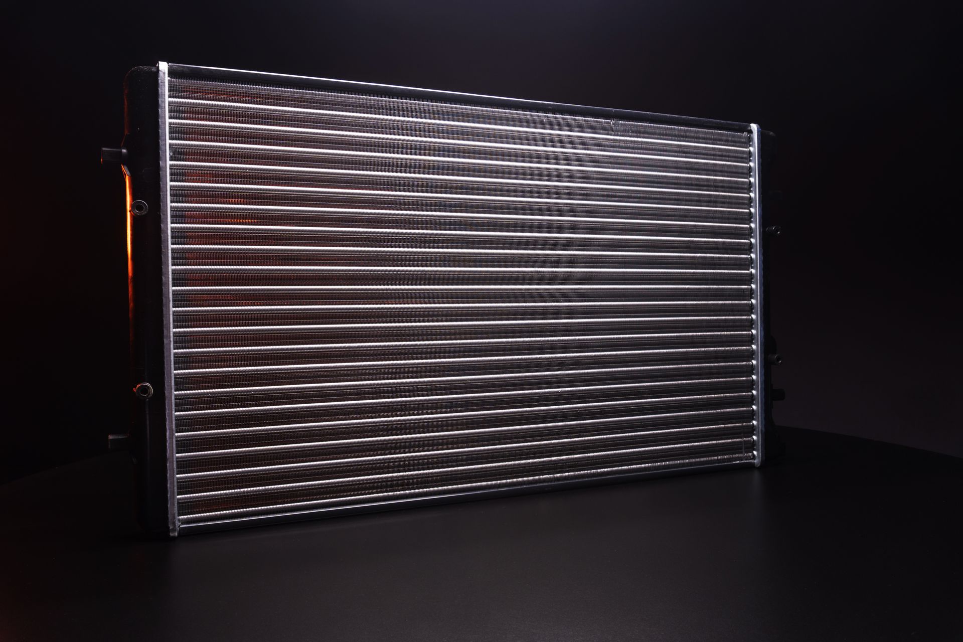Metal radiator panel with horizontal fins, lit against a dark background Metal radiator panel with horizontal fins, lit against a dark background