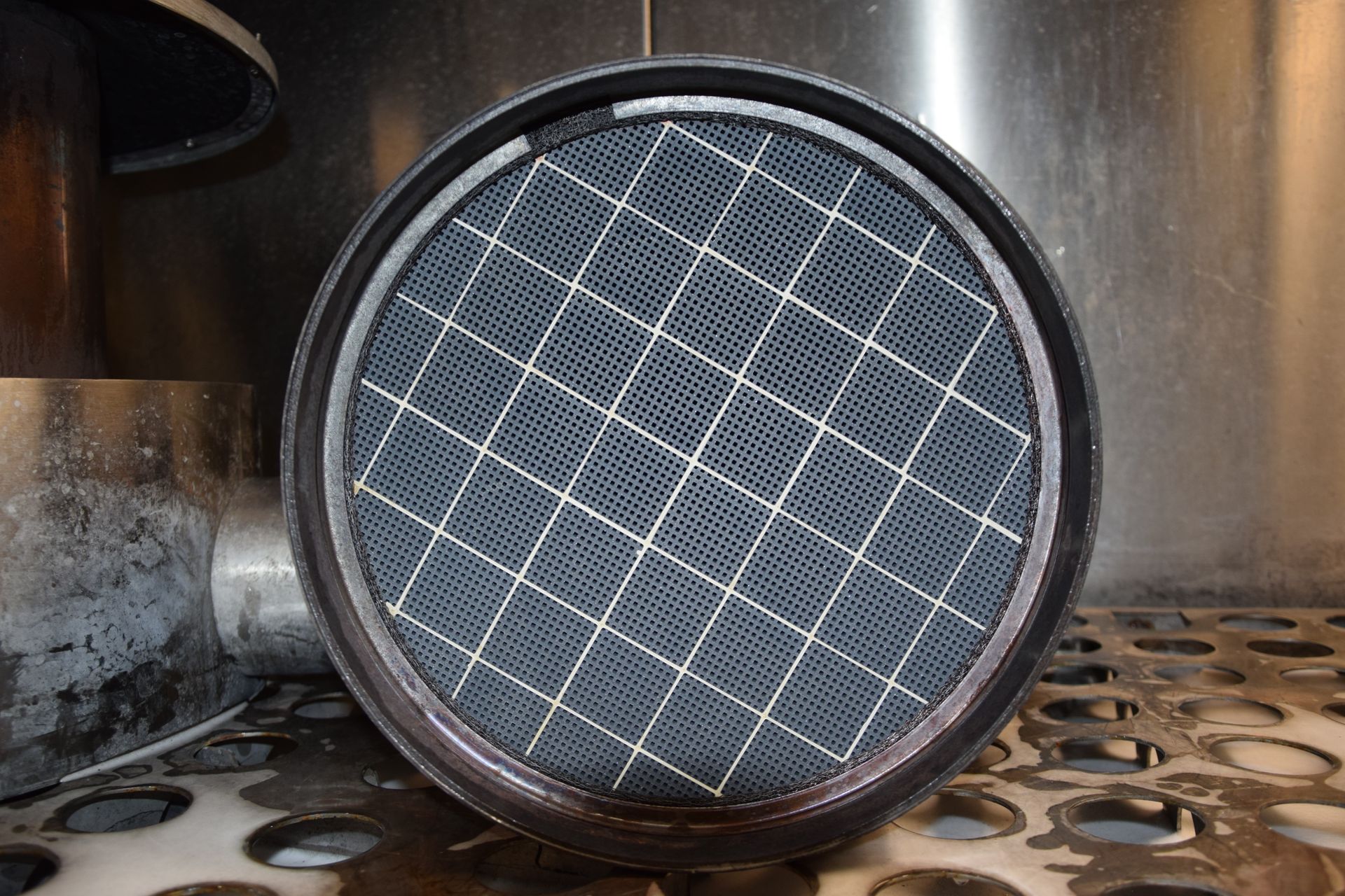 Round filter with diamond mesh pattern on a tabletop, against a dark background Round filter with diamond mesh pattern on a tabletop, against a dark background