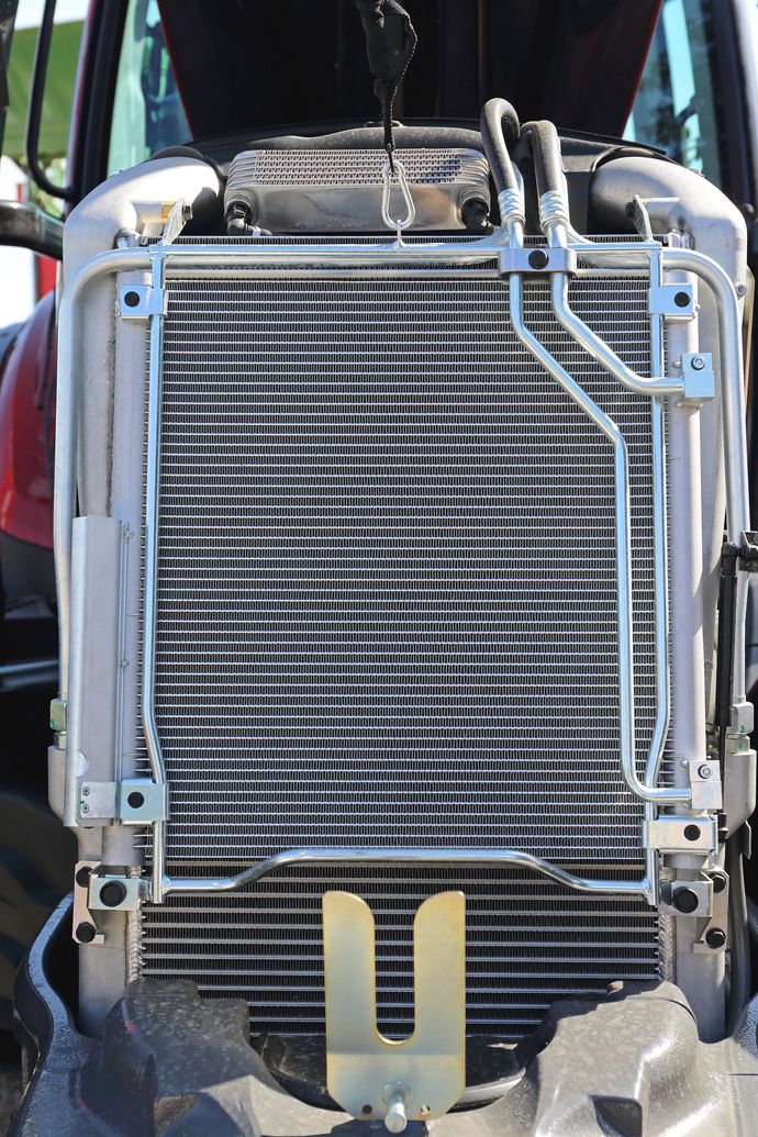 Front view of a tractor radiator with hoses and metal grille components Front view of a tractor radiator with hoses and metal grille components