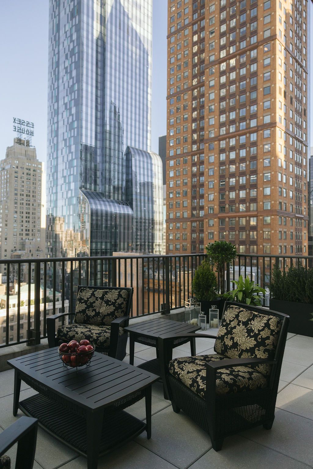 Balcony patio with black wicker chairs and table overlooking city skyscrapers