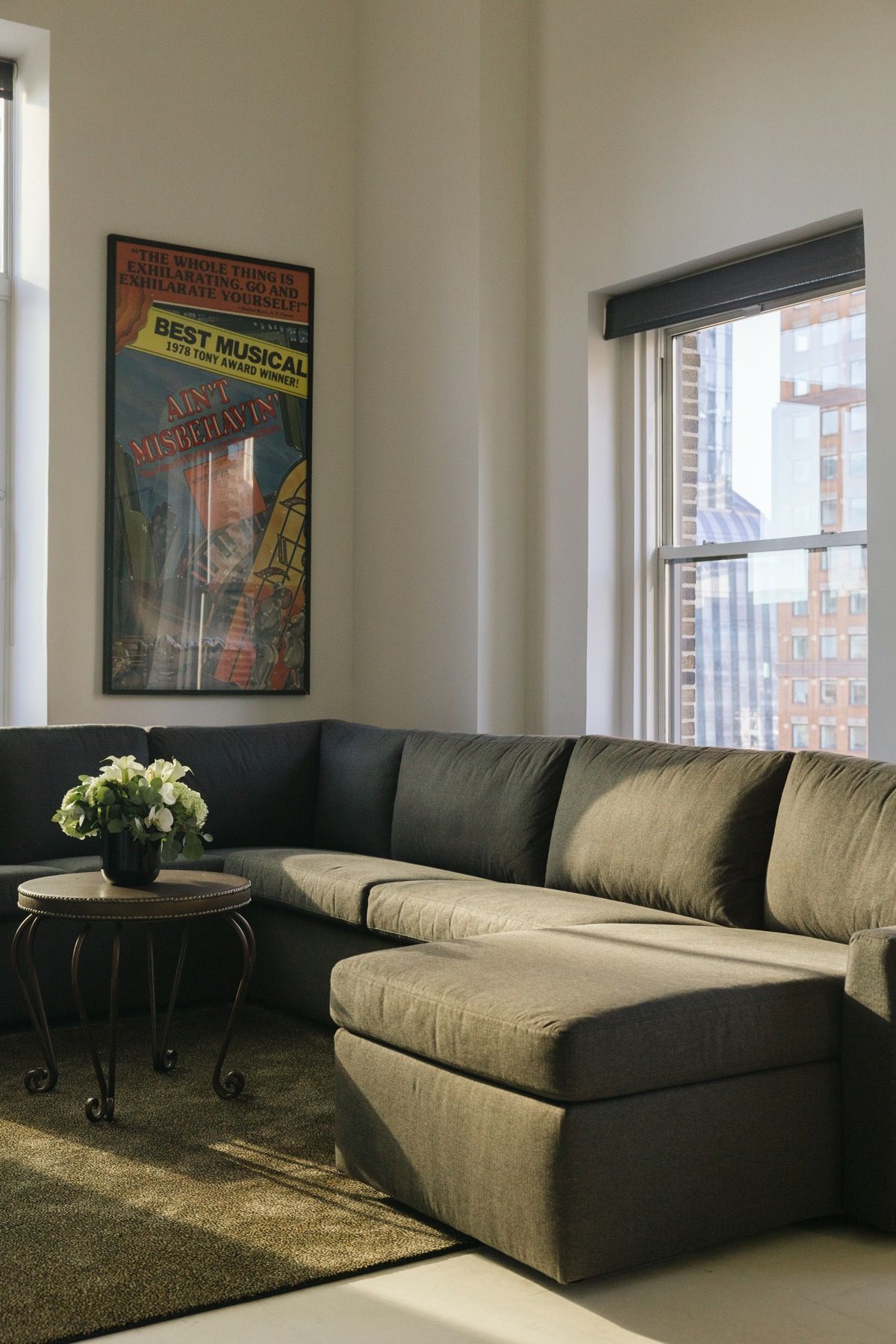 Modern living room with a gray sectional sofa, coffee table, rug, and window light