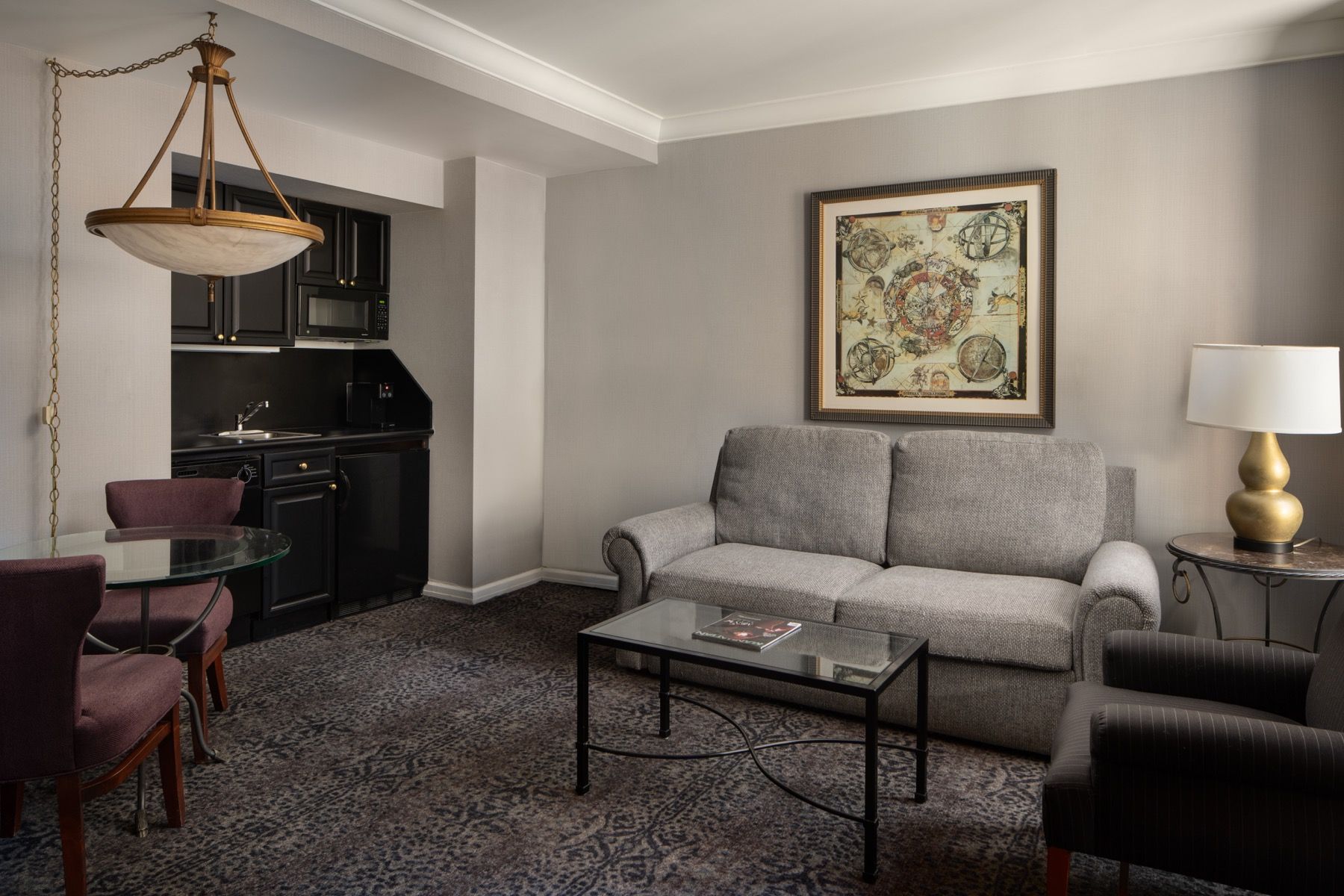 Modern living room with gray sofa, black coffee table, armchair, lamp, and framed wall art
