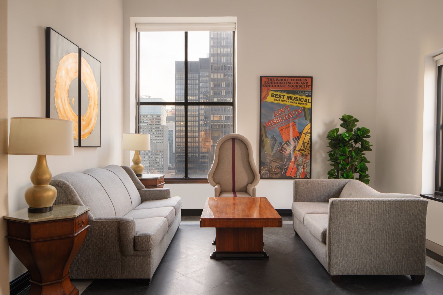 Bright modern living room with two gray sofas, wood coffee table, city-view window, and colorful wall art