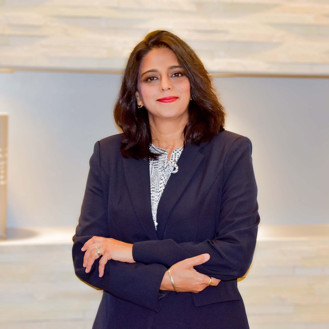 A woman in a suit is standing with her arms crossed